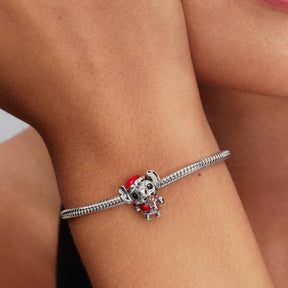 Pandora hopeinen Stitch-jouluhela rannekorussa, punatonttuasuun pukeutunut hahmo pitää piparkakkua tassuissaan