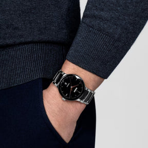 Rado automaattinen rannekello mustalla kellotaululla ja teräksenvärisellä rannekkeella ranteessa