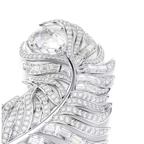 Swarovski höyhenenmuotoinen rintakoru vaaleaksi rodinoitua metallia ja säihkyviä kirkkaita zirkoneja lähikuvassa