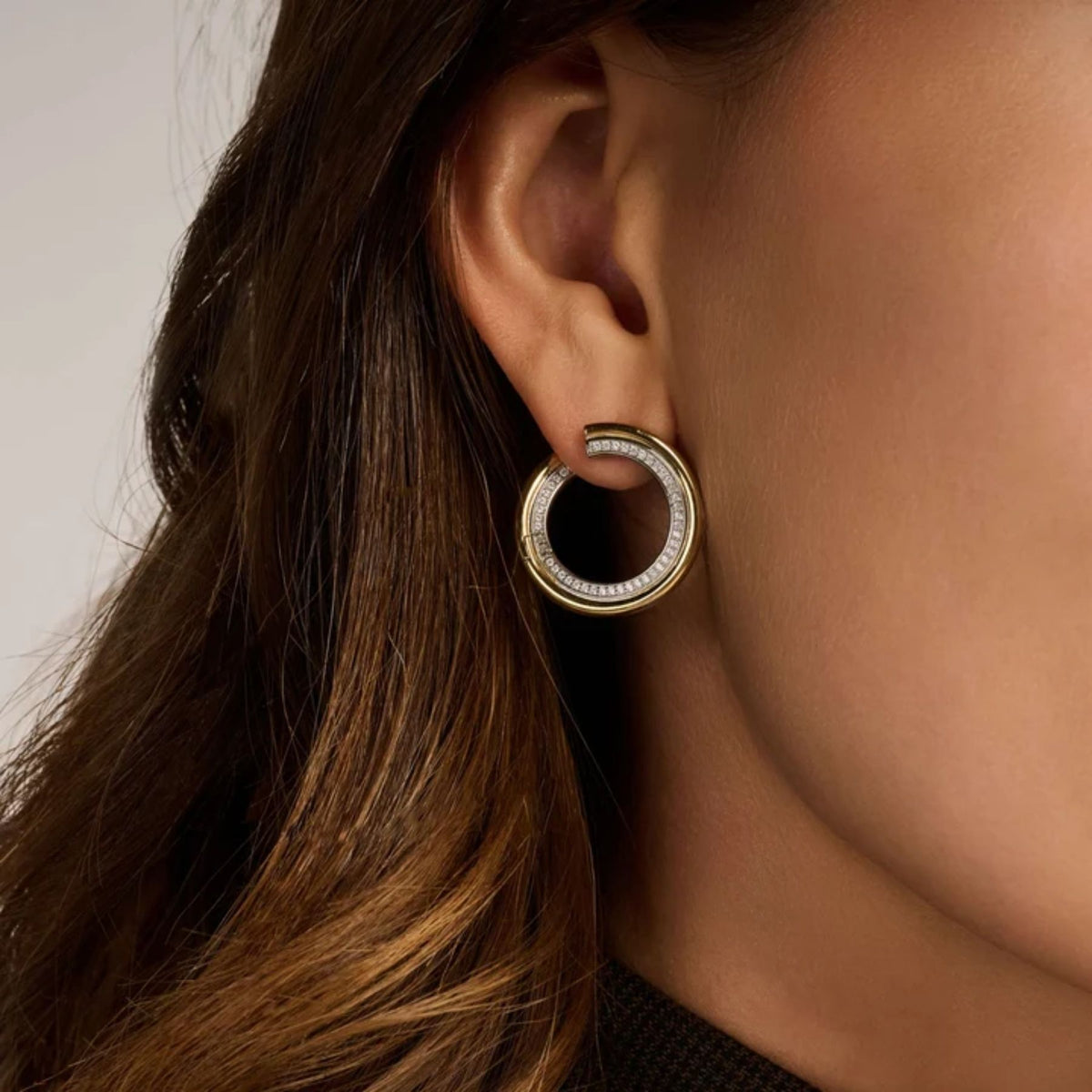 Ti Sento kaksivärinen rengaskorvakoru korvassa, keltakullattu ulkorengas ja zirkonein koristeltu hopeinen sisärengas